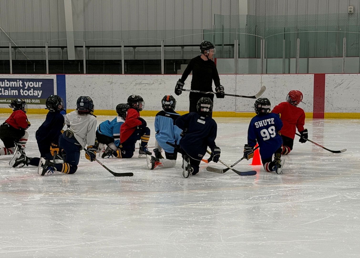 Players kneeling on the ice listening to coach at 7-Chiefs session